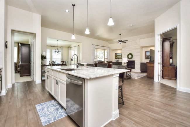 Kitchen featuring a center island with sink, a sink, stainless steel dishwasher, white cabinets, and ceiling fan | Image 9