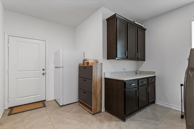 Kitchen with light countertops, dark brown cabinets, freestanding refrigerator, baseboards, and fridge | Image 32