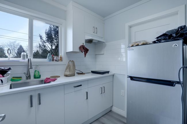 Kitchen with a healthy amount of sunlight, tasteful backsplash, a sink, and freestanding refrigerator | Image 29