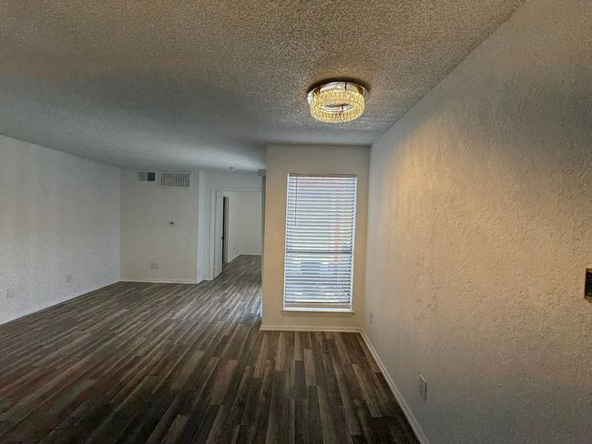 Empty room featuring a textured wall, wood finished floors, and a textured ceiling | Image 6
