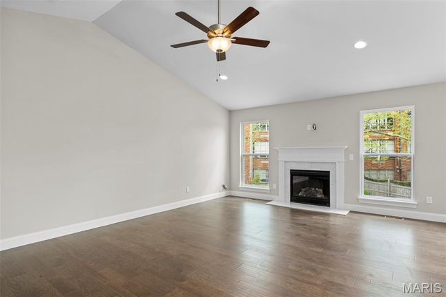 Unfurnished living room featuring lofted ceiling, a ceiling fan, recessed lighting, a fireplace with flush hearth, and baseboards | Image 11