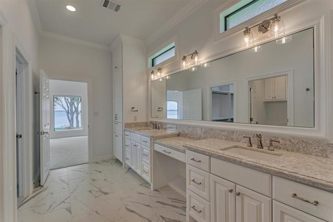 Another view of the primary bath reveals the first primary bedroom just beyond. Elevated horizontal windows allow natural light to gently filter in while maintaining a sense of privacy, adding to the room’s serene and spa-like atmosphere. | Image 24
