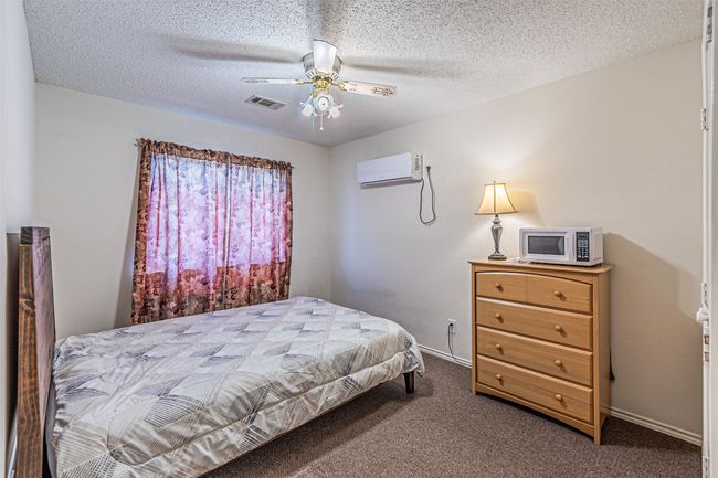 Bedroom featuring a wall mounted air conditioner, carpet flooring, a textured ceiling, and a ceiling fan | Image 25