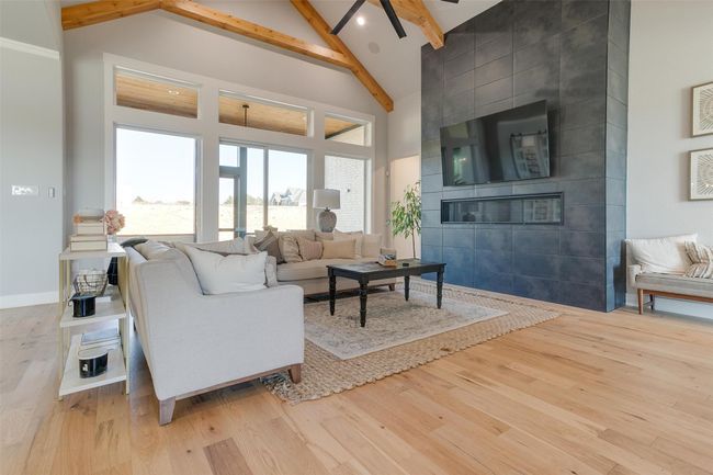 Living room with a tile fireplace, high vaulted ceiling, ceiling fan, light wood-type flooring, and beamed ceiling | Image 7