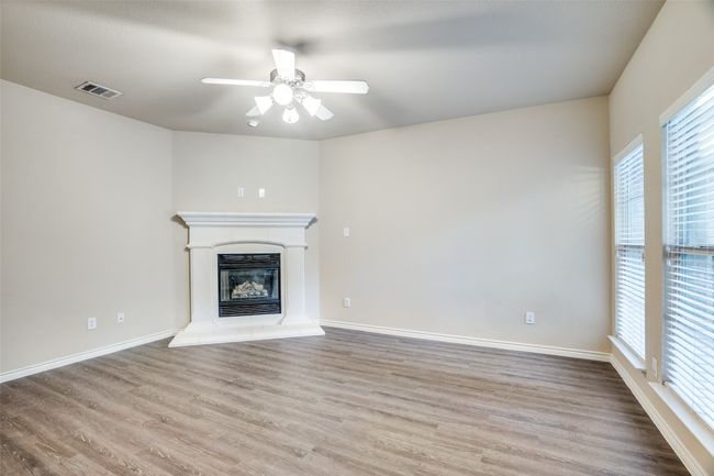 Unfurnished living room featuring wood-like finished floors, ceiling fan, and a healthy amount of sunlight | Image 4