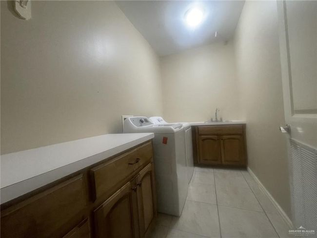 Laundry area featuring cabinet space, washer and dryer, and light tile patterned floors | Image 14