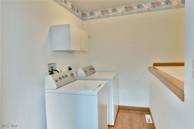 Laundry area featuring washing machine and dryer, cabinet space, and light wood-type flooring | Image 22