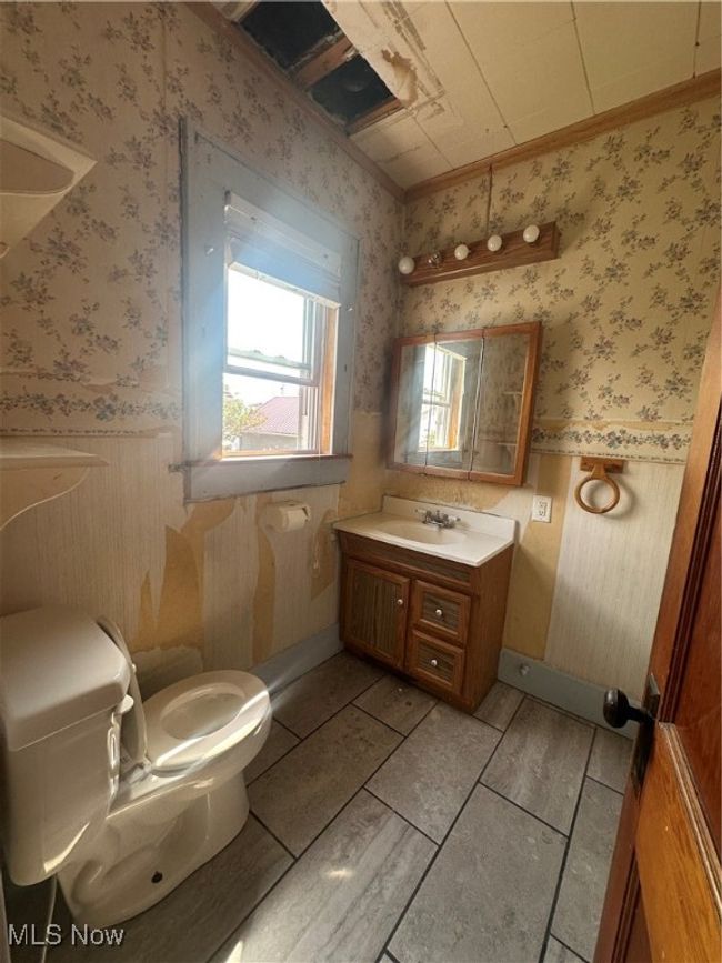 Half bath featuring a wainscoted wall, toilet, wallpapered walls, crown molding, and vanity | Image 8
