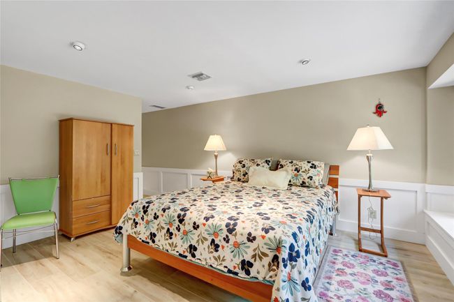 Bedroom featuring visible vents, a wainscoted wall, light wood finished floors, and a decorative wall | Image 22