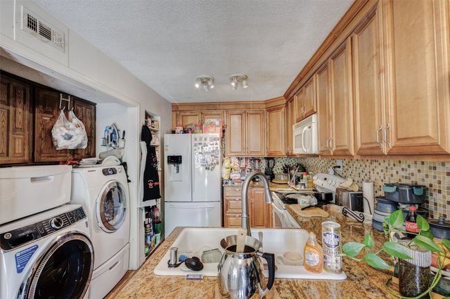 Washroom featuring washer and clothes dryer, a sink, a textured ceiling, laundry area, and visible vents | Image 12