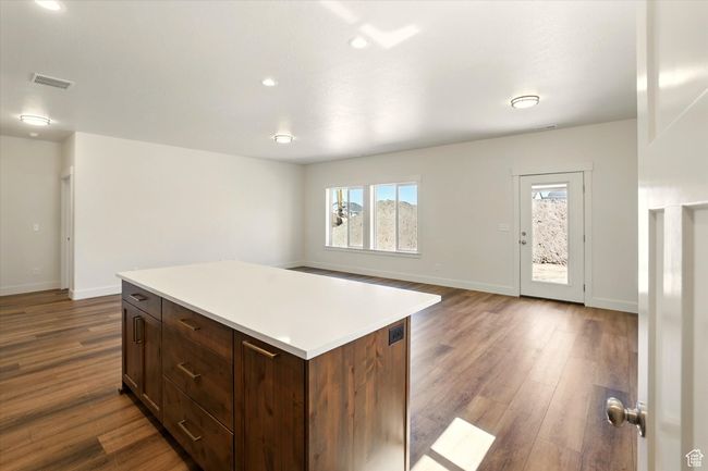 Kitchen featuring dark wood-style floors, light countertops, baseboards, a center island, and recessed lighting | Image 13