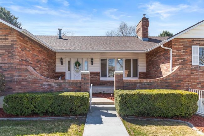 View of exterior entry with a chimney, a shingled roof, and brick siding | Image 43