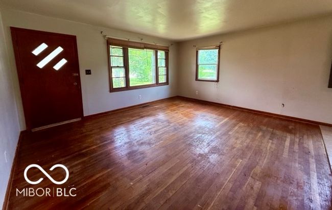 Bright living room with large picture windows and original hardwood floors, ready for your personal touch. Natural light fills the space, creating a warm and inviting atmosphere | Image 4
