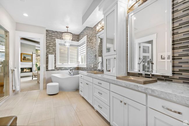 Full bath with double vanity, an inviting chandelier, a sink, and a glass covered fireplace | Image 40