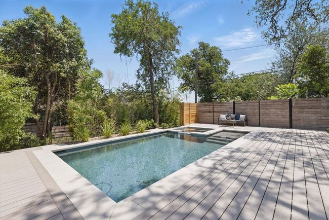 View of swimming pool with a deck, a fenced backyard, and a pool with connected hot tub | Image 33