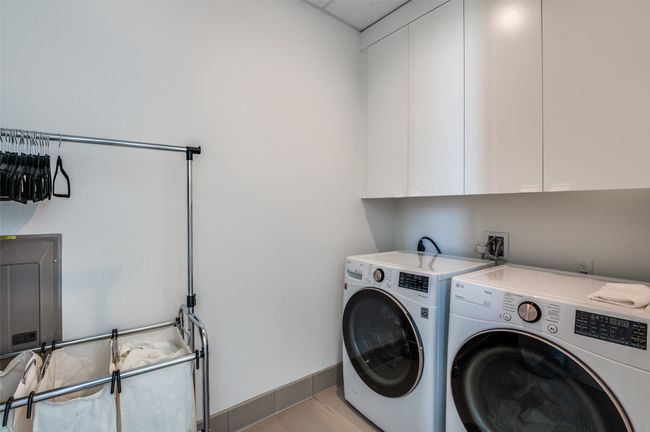 Washroom with cabinet space, washing machine and clothes dryer, light tile patterned floors, and electric panel | Image 25