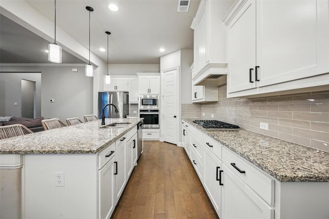 Kitchen with stainless steel appliances, tasteful backsplash, white cabinets, recessed lighting, and dark wood-style floors | Image 18