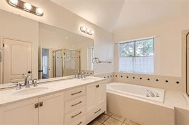 Full bathroom featuring a stall shower, a bath, double vanity, vaulted ceiling, and tile patterned flooring | Image 14