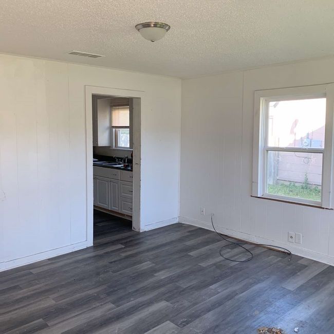 Unfurnished room featuring a textured ceiling, dark wood-style flooring, baseboards, and a sink | Image 5