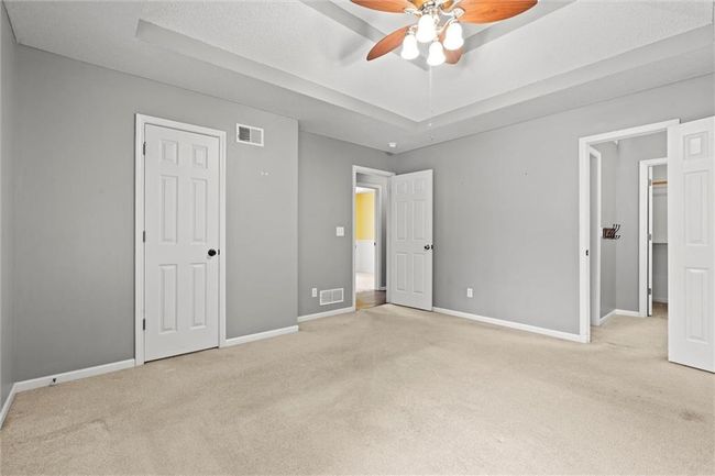 Unfurnished bedroom featuring light colored carpet, a tray ceiling, and a ceiling fan | Image 18