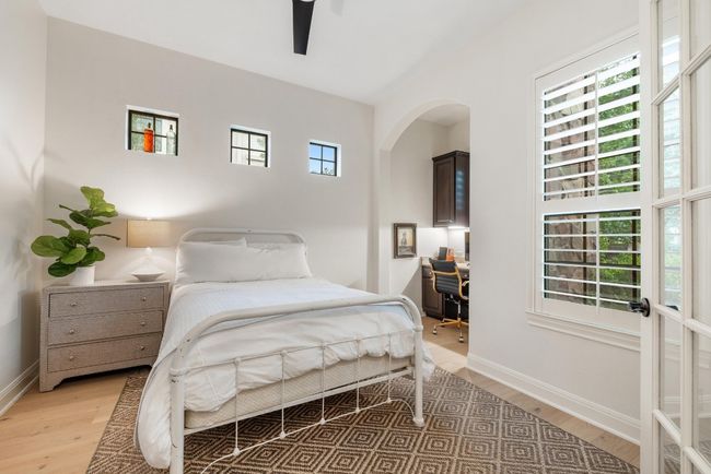 4th Bedroom or office on main level with light wood flooring, baseboards, arched walkways, and an built-in desk workspace | Image 17