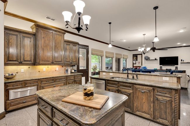 Over-sized kitchen featuring stainless steel dishwasher, a sink, warming drawer, and double ovens | Image 10