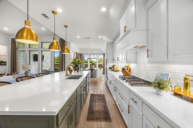 Kitchen with open floor plan, light countertops, light wood-style floors, decorative backsplash, and a large island with sink | Image 12