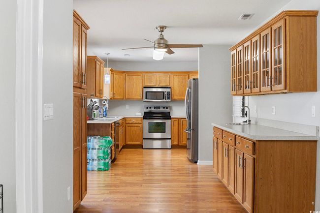 Kitchen with appliances with stainless steel finishes, a sink, ceiling fan, light wood-style flooring, and light countertops | Image 36