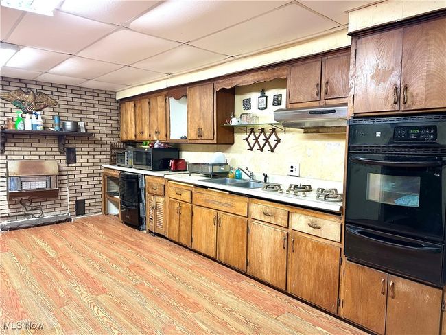 Kitchen with oven, light wood-style floors, a warming drawer, stainless steel microwave, and under cabinet range hood | Image 9