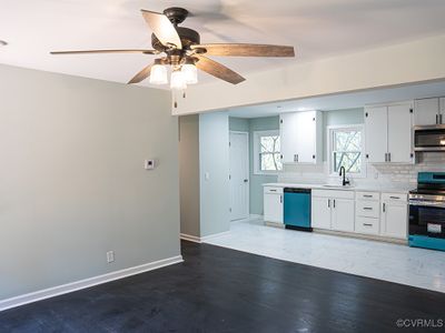 Kitchen featuring ceiling fan, decorative backsplash, white cabinets, sink, and appliances with stainless steel finishes | Image 3