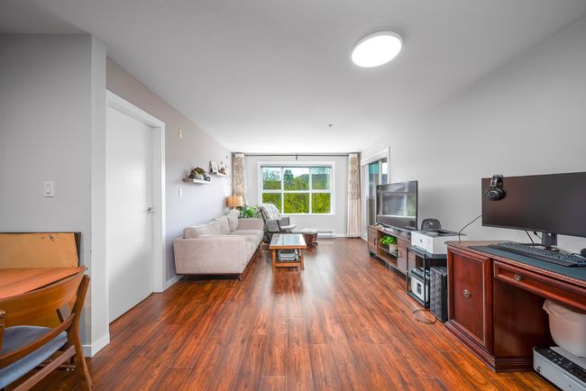 Living area featuring dark wood-type flooring, a baseboard radiator, and baseboards | Image 8