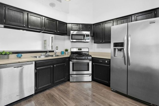 Kitchen featuring stainless steel appliances, dark cabinetry, light countertops, and dark wood-type flooring | Image 14