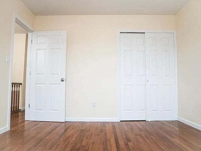 Unfurnished bedroom with wood finished floors, a closet, and baseboards | Image 11