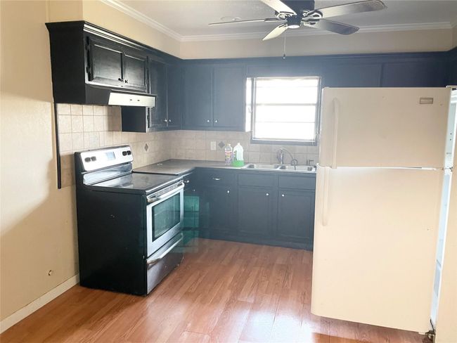 Kitchen featuring freestanding refrigerator, electric range, crown molding, light wood finished floors, and a ceiling fan | Image 4