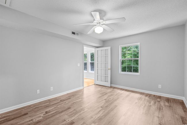 Unfurnished room with healthy amount of natural light, wood finished floors, a textured ceiling, and ceiling fan | Image 22