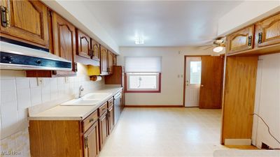 Kitchen with exhaust hood, backsplash, sink, stainless steel dishwasher, and ceiling fan | Image 3