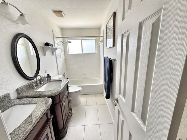 Bathroom with vanity, shower / bathtub combination, tile patterned flooring, and a textured ceiling | Image 29
