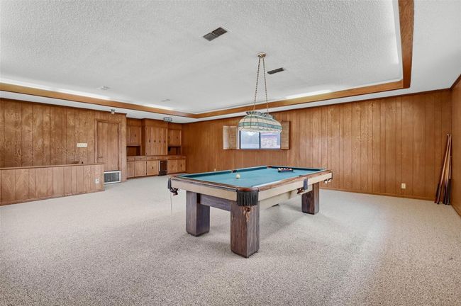 Playroom featuring a textured ceiling, wood walls, pool table, and light colored carpet | Image 28