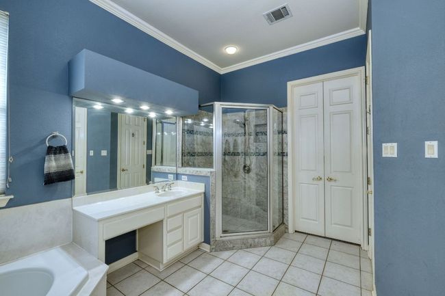 Bathroom featuring a shower stall, crown molding, tile patterned flooring, and visible vents | Image 18