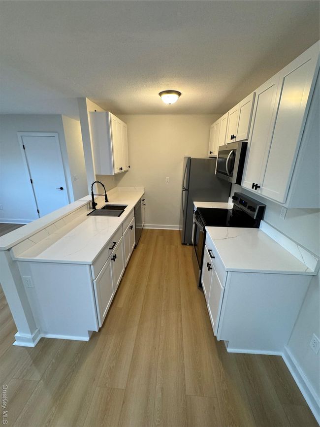 Kitchen with range, light wood-style floors, white cabinets, a peninsula, and dishwasher | Image 16