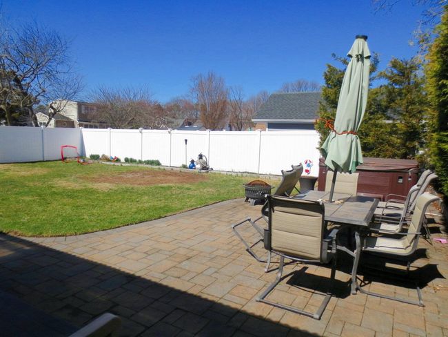 View of patio with outdoor dining space, a fire pit, a fenced backyard, and a hot tub | Image 28