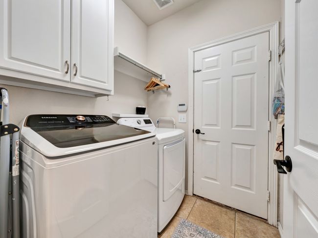 Clothes washing area with tile floors, cabinet space, and garage access door | Image 30