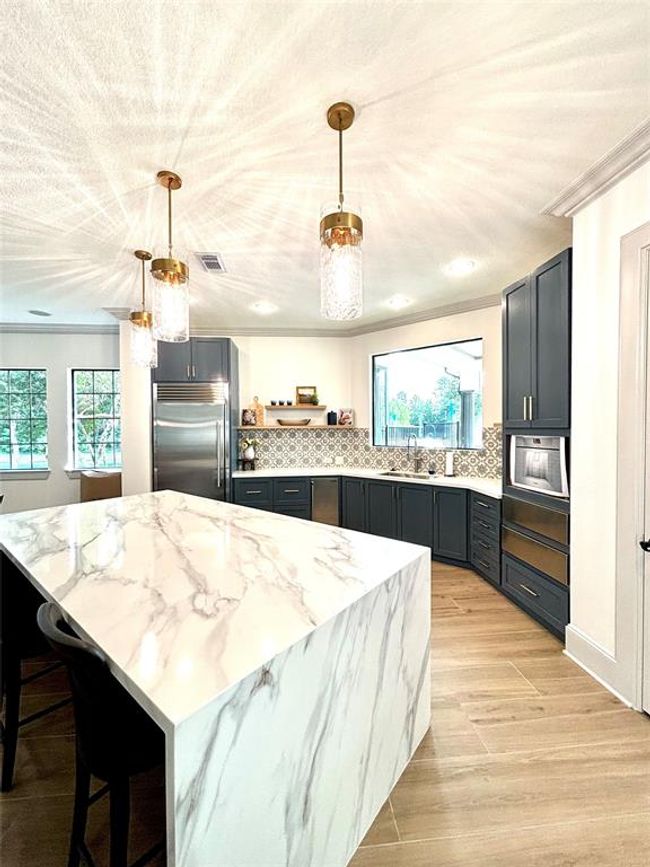 The Clubhouse at The Falls at Imperial Oaks boasts a stylish modern kitchen featuring a waterfall-edge marble island, designer lighting, stainless appliances, and elegant cabinetry—perfect for hosting private events or community gatherings. | Image 48