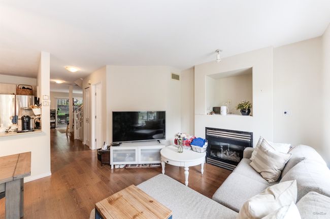 Living area with wood finished floors and a glass covered fireplace | Image 5