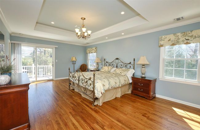 Bedroom featuring a tray ceiling, access to exterior, a chandelier, multiple windows, and wood finished floors | Image 21
