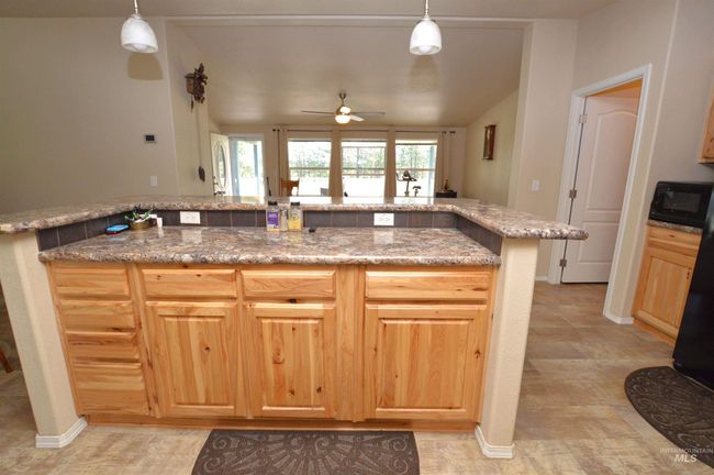 Kitchen featuring a ceiling fan, plenty of natural light, light brown cabinets, vaulted ceiling, and hanging light fixtures | Image 9