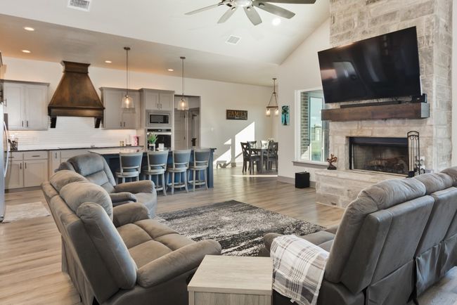 Living area with ceiling fan, visible vents, a fireplace, light wood-type flooring, and high vaulted ceiling | Image 19