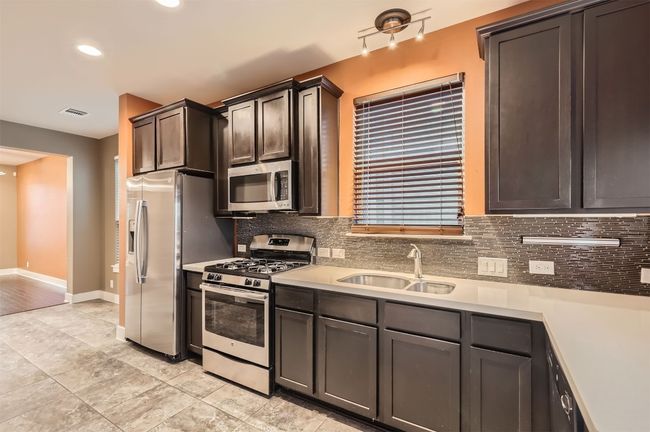 Kitchen featuring stainless steel appliances, decorative backsplash, light countertops, recessed lighting, and dark brown cabinets | Image 6