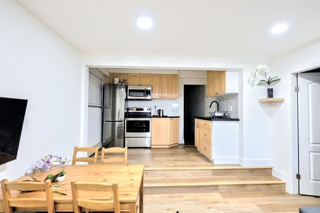 Kitchen featuring stainless steel appliances, recessed lighting, dark countertops, light wood-style floors, and a sink | Image 31