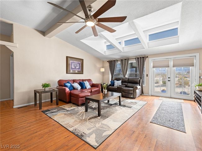 Living room with baseboards, lofted ceiling with beams, ceiling fan, and wood finished floors | Image 12